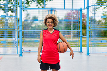 girl with afro hairstyle with a ball on a basketball court