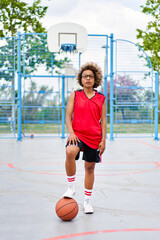 girl with afro hairstyle with a ball on a basketball court