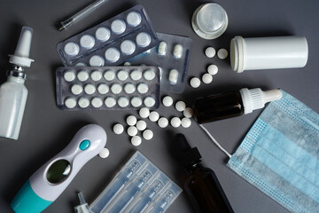 Medical blue mask, ampoule vials, tablets, nasal spray and syringe on light background