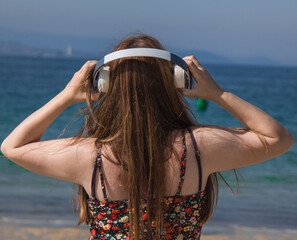 woman from behind looking at the sea with headphones