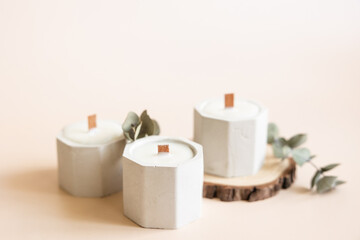 Handmade candles from paraffin and soy wax in concrete plaster candlestick with wooden wick and dry herbal isolated on pastel beige background. Copy space