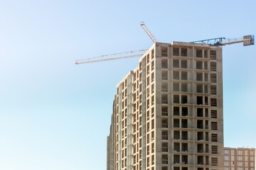 A large construction crane and a house under construction. Construction of houses in the city or after it. Selective focus