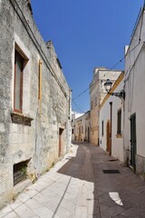 Fototapeta na wymiar A narrow street between the old houses of Presicce, a picturesque village in the province of Lecce in Italy.