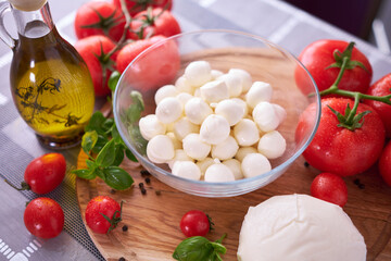 Ingredients for Caprese salad - Mini mozzarella cheese in glass bowl, tomato and basil