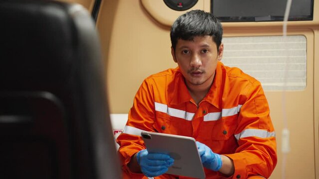 Portrait of Emergency medical technician (EMT) Asian man or paramedic smiling and looking at camera while sitting in ambulance car