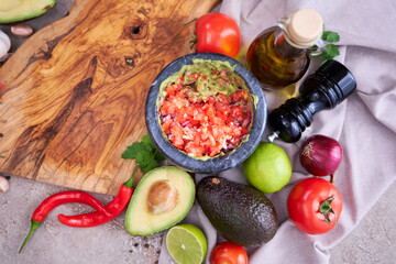making guacamole - crushed avocado in marble mortar and ingredients