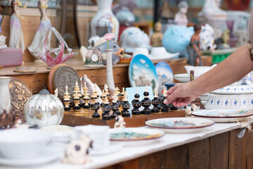 The hand of the elderly woman at the flea market touching a handmade chess piece. Zero waste, ecological concept, sustainable lifestyle.