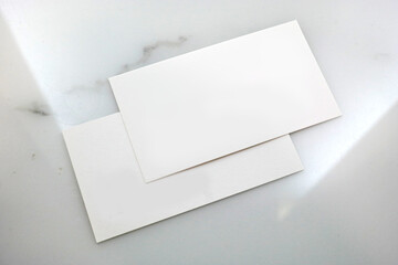 Two white business cards on a marble table