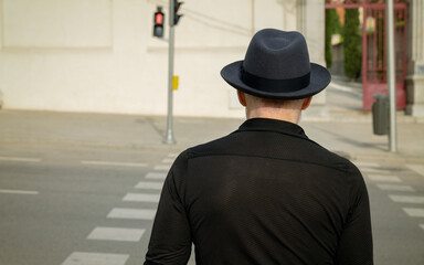 Rear view of adult man in hat on street