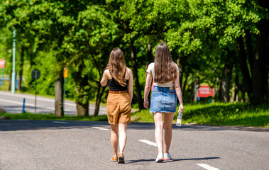 Two girlfriends walk along a path in the Park
