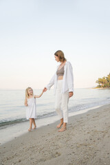 Mother and daughter walking on the beach. Family summer vacation concept.	