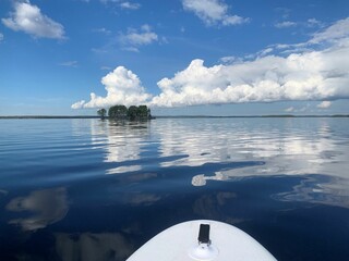 Stand up paddling on a lake towards a small island. The water is calm and it is a perfect summer...