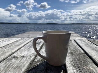 Enjoying a cup of warm drink on a wooden deck. It is a wonderful sunny day, perfect for relaxing....
