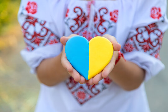 A Child Holds A Heart Of The Ukrainian Flag. Selective Focus.