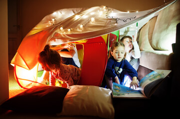 Obraz na płótnie Canvas Playing kids in tent at night home. Hygge mood.
