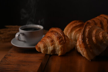 Tasty croissants and hot coffee on wooden wooden board ready to serve for breakfast. Breakfast, bread bakery products cafe concept