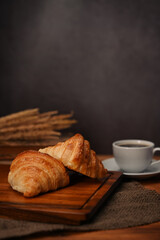 Homemade butter croissant in tray decorated with wheat on wooden table. Levitation, bread bakery products cafe concept