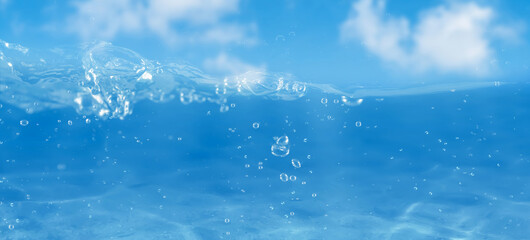 beautiful abstract water background with waterline and water splashes and drops on blue sky in...