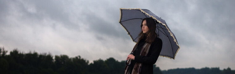 Young woman walking in the rain on a cloudy autumn day