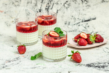 Strawberry panna cotta with mint topping with strawberry sauce on a light background. Summer yogurt...