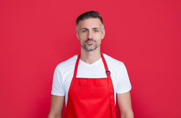 smiling mature man waiter in apron on red background