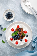 Chocolate cake, white cheesecake decorated with blueberries, cherry, brown chocolate and whipped cream