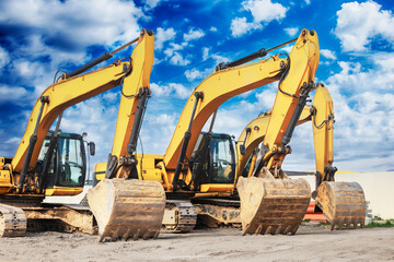 Powerful excavators at a construction site against a cloudy evening sky. earthmoving construction equipment. Lots of excavators.