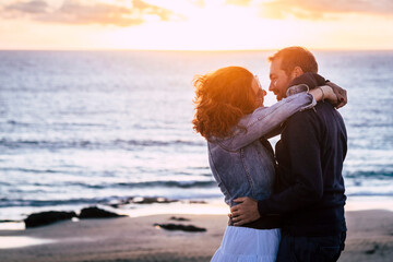 Romantic mature couple in love kissing outdoor against an amazing sunset at the beach with ocean...