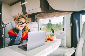 Off grid van life and digital nomad lifestyle. Cute modern woman working on laptop inside a camper...