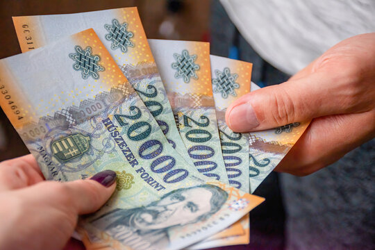 Young woman gives money to a young man. Payment concept, Hungarian forint.