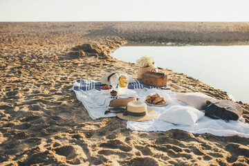 Beautiful picnic with fresh fruits, lemonade and croissants on the beach at sunset.