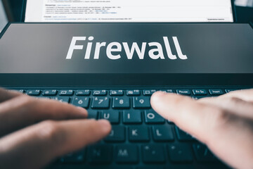 the inscription firewall on the laptop screen. Digital cybersecurity and network protection concept. Virtual locking mechanism to access shared resources. Businessman working at laptop