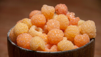 Frambuesas amarillas en cuenco marrón en mesa de madera