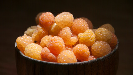 Frambuesas amarillas en cuenco marrón en mesa de madera