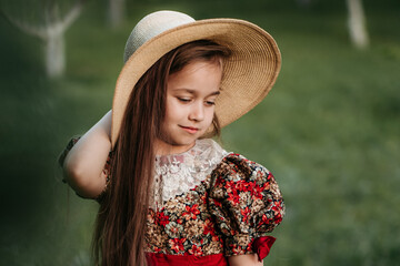 Beautiful girl in a vintage dress 7-8 years old posing in the garden. Beautiful spring garden. The concept of a happy childhood, peace and happiness.