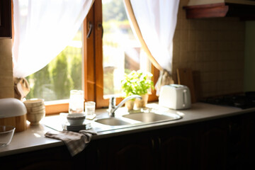 Blurred view of stylish kitchen interior with sink near window