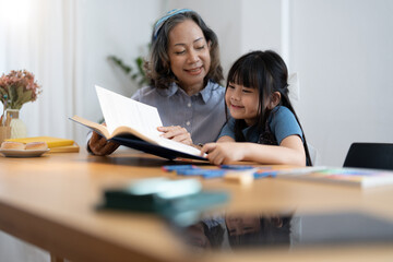 grandchild granddaughter grandma grandmother reading book girl senior. asian people.