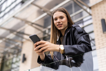 Young woman uses smartphone outdoors in big city