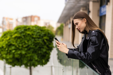 Business woman uses by mobile phone outdoors walking along the street