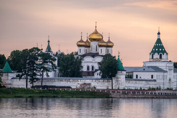 summer landscape with ancient churches against the backdrop of a forest and a river at sunset