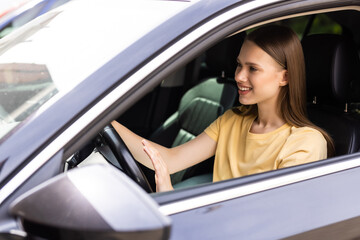Young woman hand pressing the horn button while driving a car through the road.