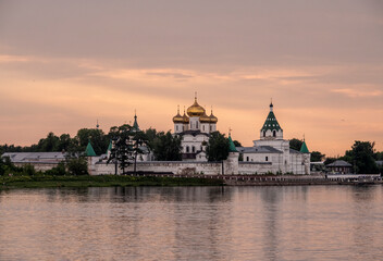 Fototapeta premium summer landscape with ancient churches against the backdrop of a forest and a river at sunset