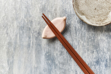 Wooden chopsticks and chopstick rest on rustic wooden background. Top view. Close up. Copy space.