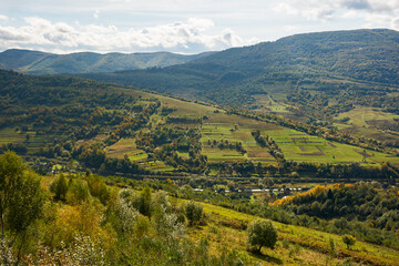 Obraz premium carpathian countryside landscape in early autumn. beautiful mountain landscape in dappled light. warm sunny day with clouds on the sky