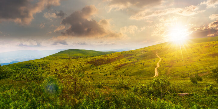 carpathian mountain landscape in summer at sunset. dirt road and hiking trail track. panoramic view of a hilly countryside in evening light. vacation and active lifestyle concept