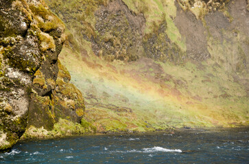 Obraz na płótnie Canvas Rainbow appearing above the water near a waterfall in Iceland