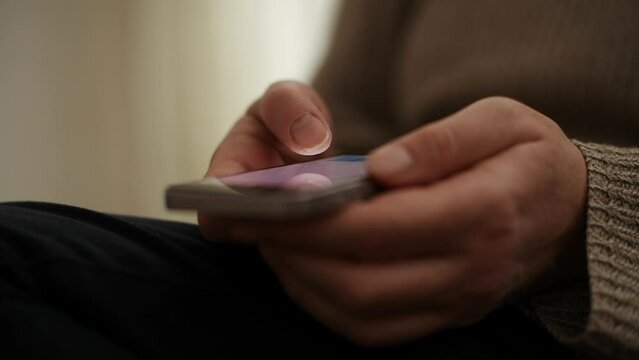 Closeup of female hands using smartphone for communication in living room