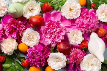 Beautiful composition of pink rose and peony flowers, fruits, ceramic birds as background. Top view, close-up, flat lay. Floral background.