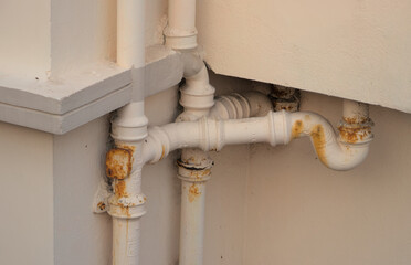 Repainted rustic pipes of drainage system from back of a building