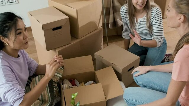 Three female friends unpacking boxes in new home.